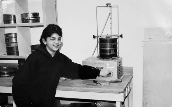 Photo of Gabrielle Christman working near a table with equipment in her fathers engineering lab