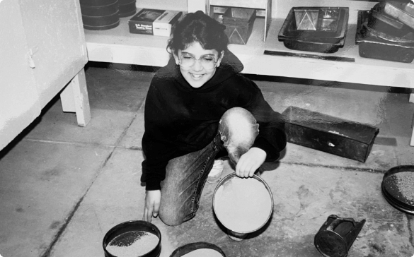 Photo of Gabrielle Christman as a young adult tinkering with equipment in her dads engineering lab